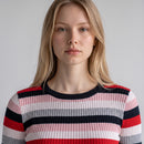 A close-up of a woman wearing a ribbed knit crewneck sweater with horizontal stripes in red, pink, gray, and navy blue against a light gray background.