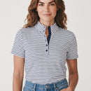 A woman wearing a short-sleeve polo shirt with navy blue and white horizontal stripes, featuring a split collar and a three-button placket, paired with blue jeans against a light gray studio background.