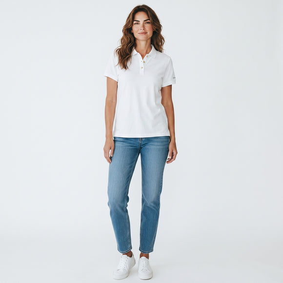 A woman modeling a white short-sleeve polo shirt with light blue jeans and white sneakers, standing against a plain white studio background.